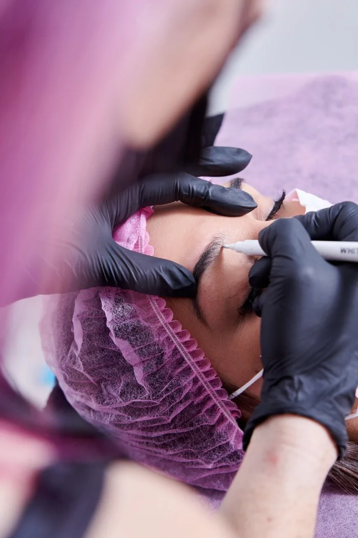 Permanent makeup artist using a PMU machine to perform eyebrow microblading on a client at RH Beauty Lounge in Las Vegas