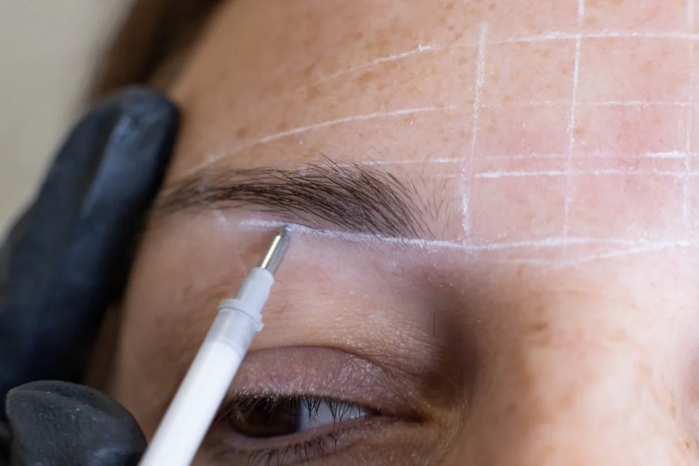 permanent makeup artist mapping brow shape during PMU consultation at RH Beauty Lounge in Las Vegas